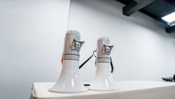 istock Two white - gray MEGAPHONE are laid on cream table in empty hall, ready to used for event corona virus vaccine booster in Bangkok, Thailand. 1455955008