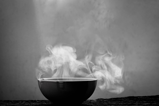 Bowl of hot soup on black background