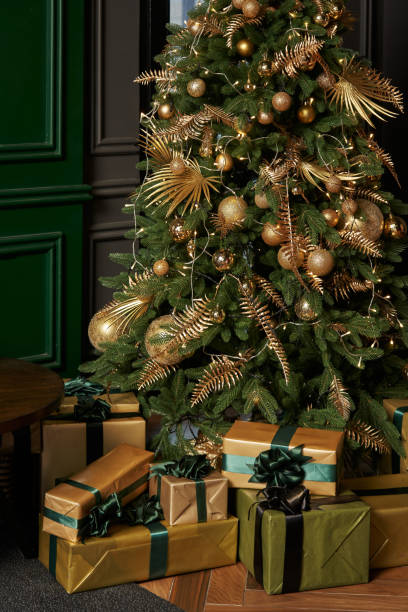 istock beautiful christmas tree with golden decorations and gifts in boxes underneath 1455956741