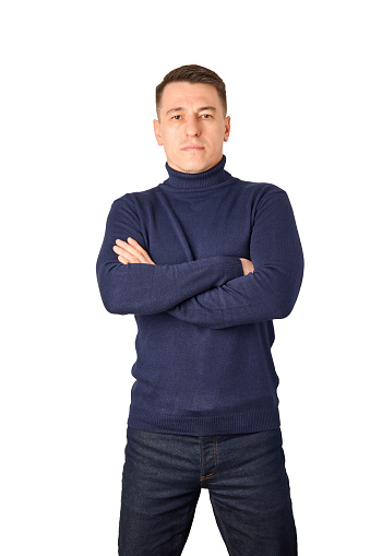 Young man wearing blue turtleneck sweater and jeans stands on the white background