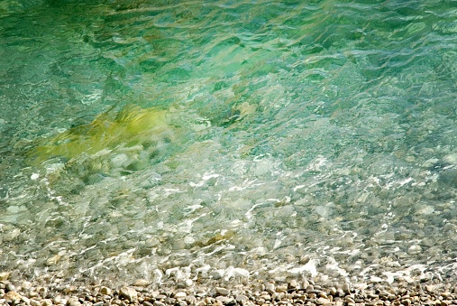 Beautiful clear blue-green sea washing up on a peble beach