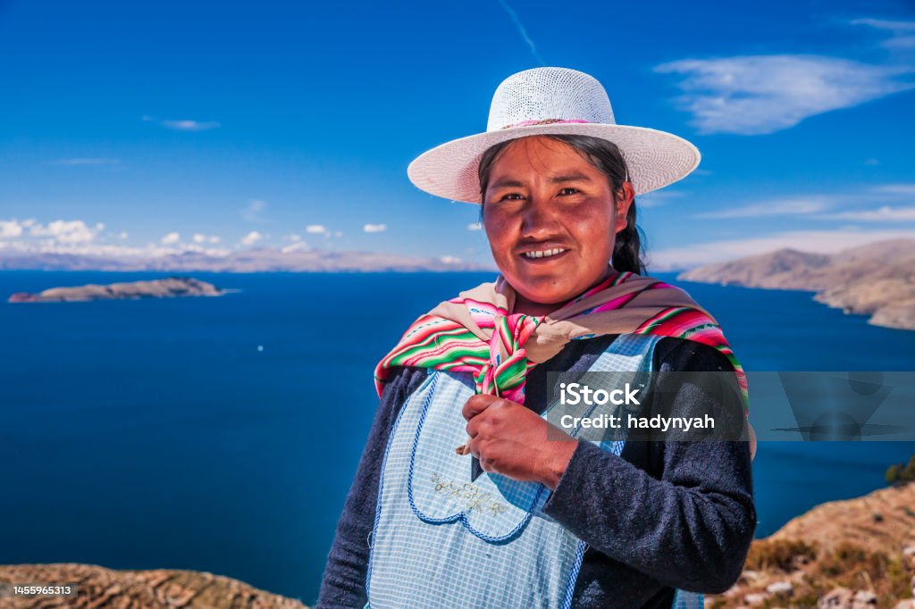 Aymara woman on Isla del Sol, Lake Titicaca, Bolivia Portrait of Aymara woman, Isla del Sol (Island Of The Sun), Lake Titicaca, Bolivia. Isla del Sol is an island in the southern part of Lake Titicaca. It is part of the modern Plurinational State of Bolivia. Geographically, the terrain is harsh; it is a rocky, hilly island. There are no motor vehicles or paved roads on the island. The main economic activity of the approximately 800 families on the island is farming, with fishing and tourism augmenting the subsistence economy. Of the several villages, Yumani and Cha'llapampa are the largest.There are over 80 ruins on the island. Most of these date to the Inca period circa the 15h century AD. Archaeologists have discovered evidence that people lived on the island as far back as the third millennium BCE. Many hills on the island contain agricultural terraces, which adapt steep and rocky terrain to agriculture. Among the ruins on the island are the Sacred Rock, a labyrinth-like building called Chicana, Kasa Pata, and Pilco Kaima. In the religion of the Incas, it was believed that the sun god was born here. Adult Stock Photo