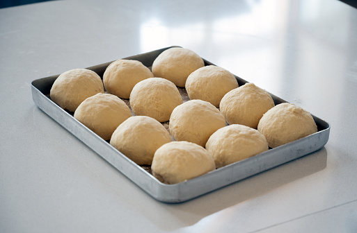 Prepared bread dough in a tray on the white table