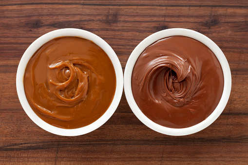 Top view of two bowls side by side with dulce de leche and chocolate spread