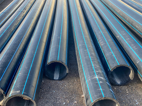 High angle view of several plastic water pipes side by side on the ground