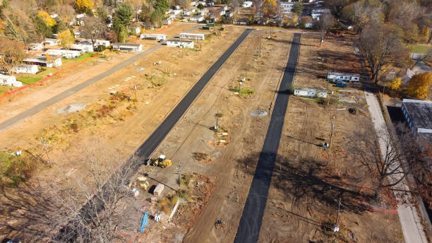istock Top view large mobile home park construction site with private concrete street, slab foundation, heavy machines and row of completed manufactured houses in Rochester, New York, USA 1455973500