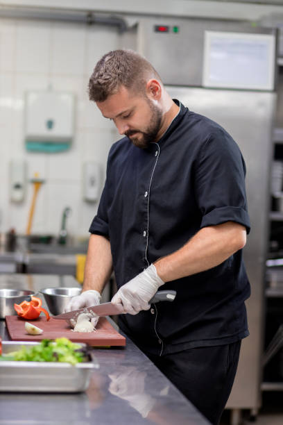 istock Professional chef in uniform cut fresh vegetables in kitchen. Cook man cooking delicious garnish for clients in restaurant. Culinary concept 1455975695
