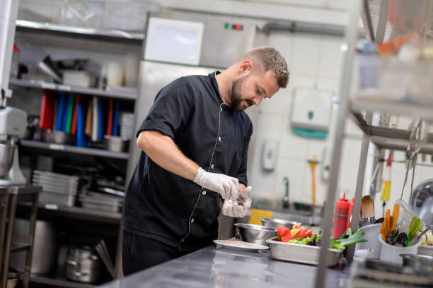 istock Professional chef in uniform cut fresh vegetables in kitchen. Cook man cooking delicious garnish for clients in restaurant. Culinary concept 1455975703