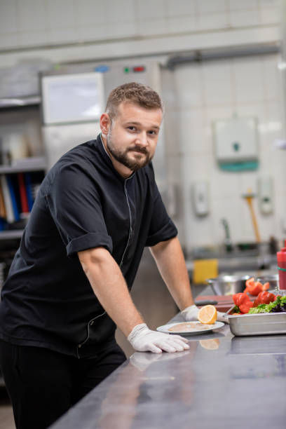 istock Professional chef in uniform cut fresh vegetables in kitchen. Cook man cooking delicious garnish for clients in restaurant. Culinary concept 1455975806