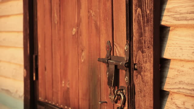 Old barn door with a padlock and a metal latch or bolt, tilt shot