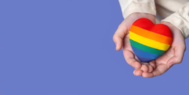 istock Close up rainbow hearts in child's hands. Top side view. Banner with copy space for design and text advertisement over purple blue background. Health insurance, donation charity, world heart day, appreciation, world children day 1455978978