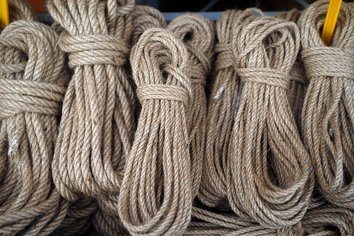 Rope tied ship on background of red ship side. Ropes hanging from fishing ship or yacht, close up.
