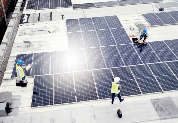 istock Solar energy, construction and employees building solar panels in collaboration for sustainability, maintenance and engineering. Teamwork, manufacturing and roof construction working on clean energy 1455979203