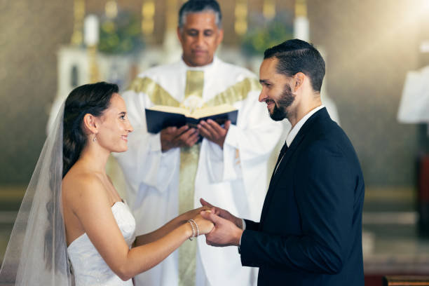 istock Couple getting married, wedding vows and love commitment at the alter of church during marriage ceremony. Happy bride, groom and Christian priest performing rites, religious and spiritual connection 1455979383