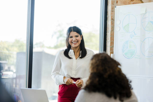 istock Female employees smile and interact during budget presentation 1455980063