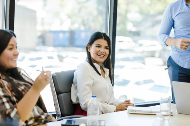 istock Female employees smile and chat before unrecognizable man begins presentation 1455980081