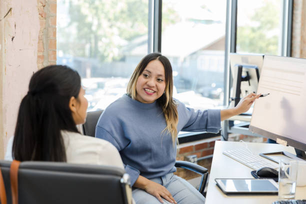 Two young adult women work together on project