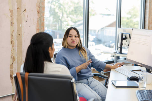 istock Young adult female co-workers discuss upcoming presentation 1455980104