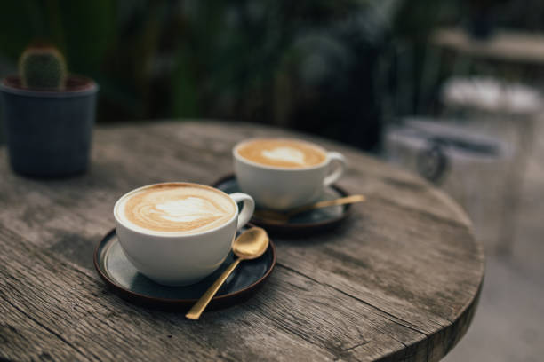 屋外の木製のテーブルの��上に熱いカプチーノ2杯。 - coffee heart shape coffee cup cup ストックフォトと画像