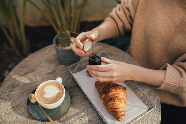 istock Young woman drinking cappuccino, eating fresh croissant with jam. 1455981380