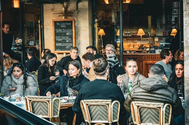 People sitting outside a cafe in Paris, France Paris, France – November 13, 2022: The people sitting outside a cafe in Paris, France busy restaurant tables stock pictures, royalty-free photos & images