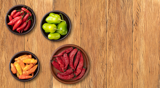 Assorted peppers over wooden table with copy space.