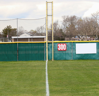 Looking down the third base foul line to the foul pole 300 yards away on a grass baseball field.