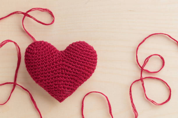 木の背景に糸でかぎ針編みのアミグルミピンクの赤いハート。バレンタインデー - nobody wool multi colored love ストックフォトと画像