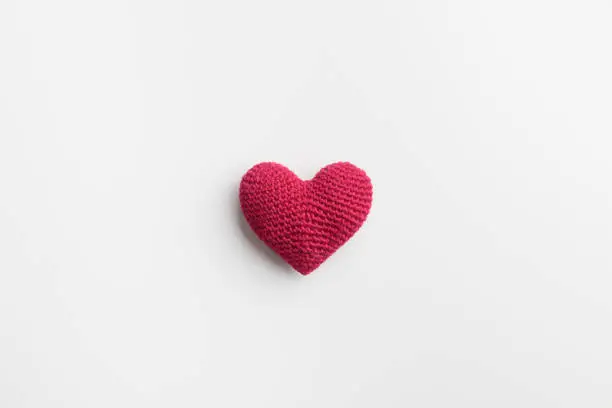 Crocheted amigurumi pink red heart on a white background. Valentine's day banner with a copyspace