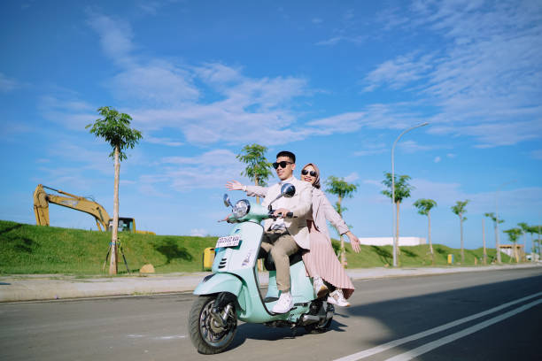 a teenage couple riding a Vespa motorbike Makassar, Indonesia - March 17, 2022 : man and woman riding a Vespa motorbike on the highway malay couple full body stock pictures, royalty-free photos & images