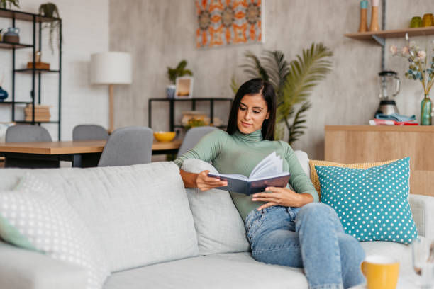 istock Young Woman Sitting On The Sofa And Reading A Book 1455992584