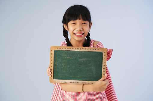 girl holding blank chalkboard against gray background