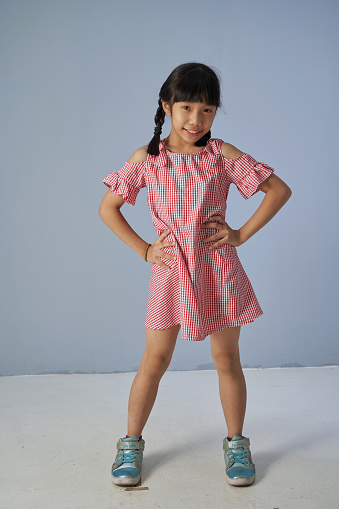 Full length of happy and funny face expression asian little child girl dress in casual standing against gray background
