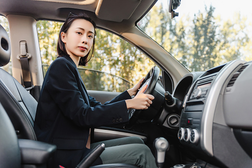 Asian woman driving a car and smiling.A young success happy woman is driving a car.