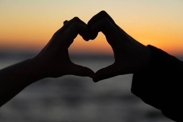 istock Silhouette of hands making heart against sunset sky 1455998144