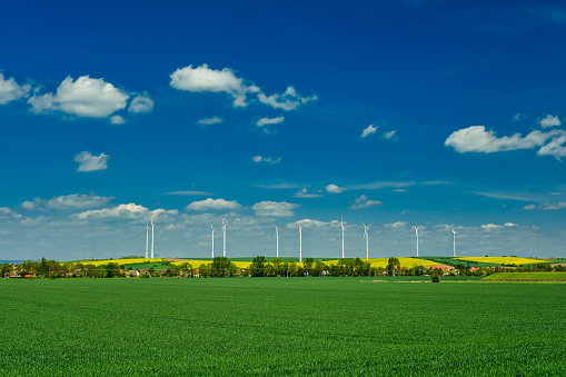 Wind electric turbines in agricultural wheat field in countryside. Deutchland.