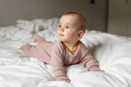Cute baby girl lying on front on the bed at home