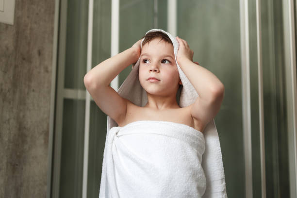 Happy boy drying himself with a towel after shower in the bathroom