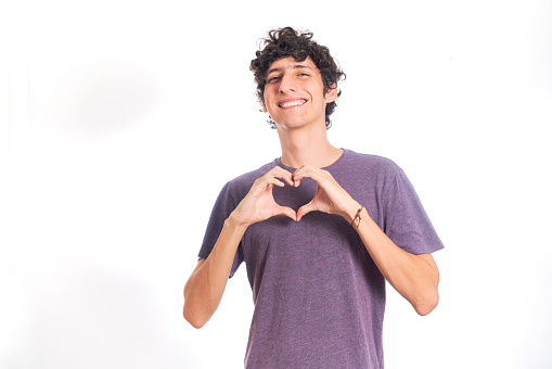 Young Hispanic man making heart shape with his hands. Isolated on white background.