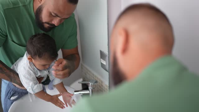 Father helping his son wash his hands at home