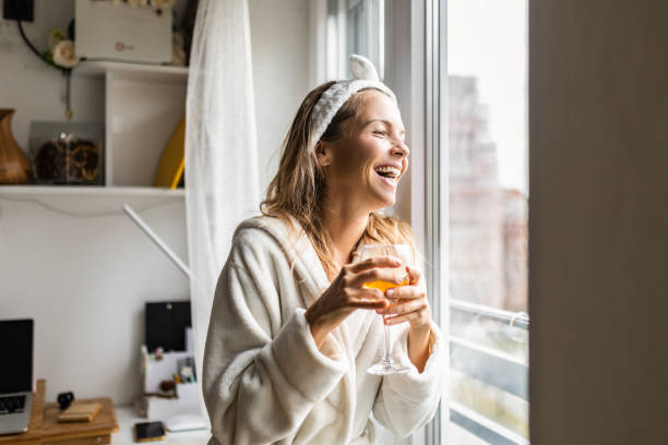 istock Attractive young woman at home drinking white wine looking through window 1456007490