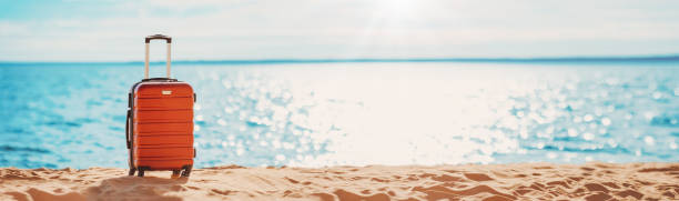 istock Panoramic view of the seacoast with suitcase on the sandbeach. 1456010722