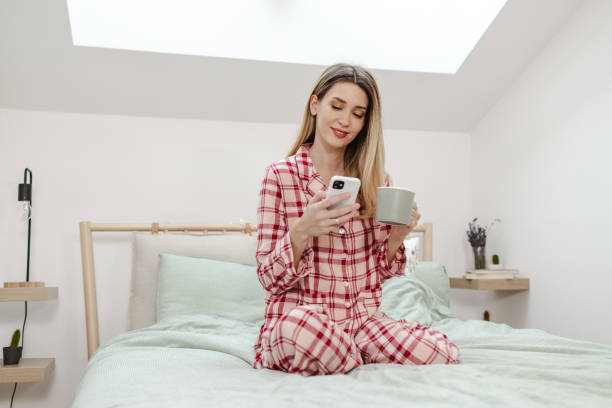 istock Young woman relaxing in bed and using smart phone 1456012487