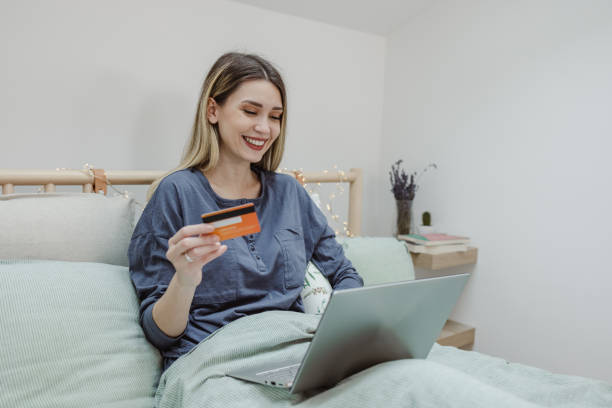 istock Young woman is using laptop for e-commerce activity in bed 1456013591
