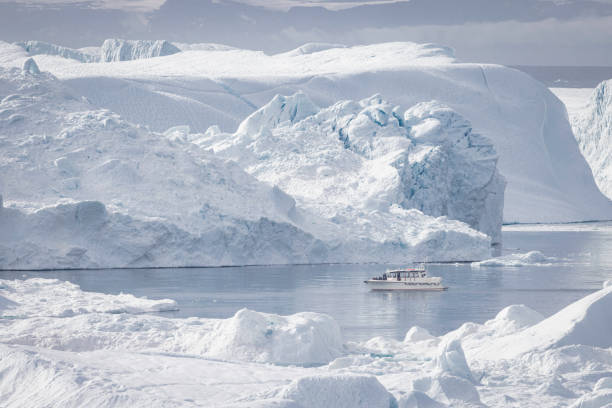 istock small boats sailing near big icebergs 1456015901