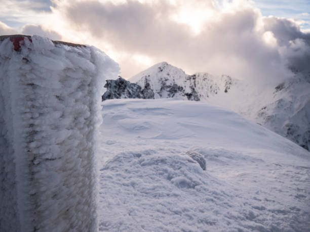 An icy border mark on top of a mountain. In the background you can see the tops of the mountains in the clouds. Tatry mountains, Poland