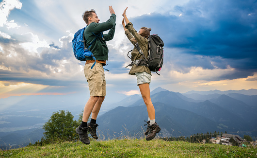 Young couple on top of the mountain giving high five for success. Success and healthy lifestyle concept.