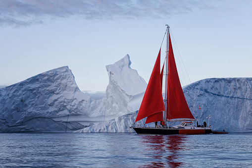 small boat sailing near big icebergs in artic polar circle