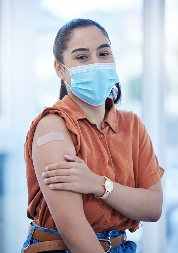 Covid, vaccine and health with woman and bandaid for medical safety, wellness and virus protection. Medicine, patient and face mask with girl and bandage on arm for injection, pandemic and treatment