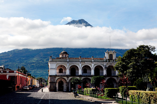 A view of the centre of the town and it's colonial buildings,  of Antigua, a famous and popular destination for travellers and backpackers, deserted of people - and in the background the Acatenango volcano, rising above the clouds.